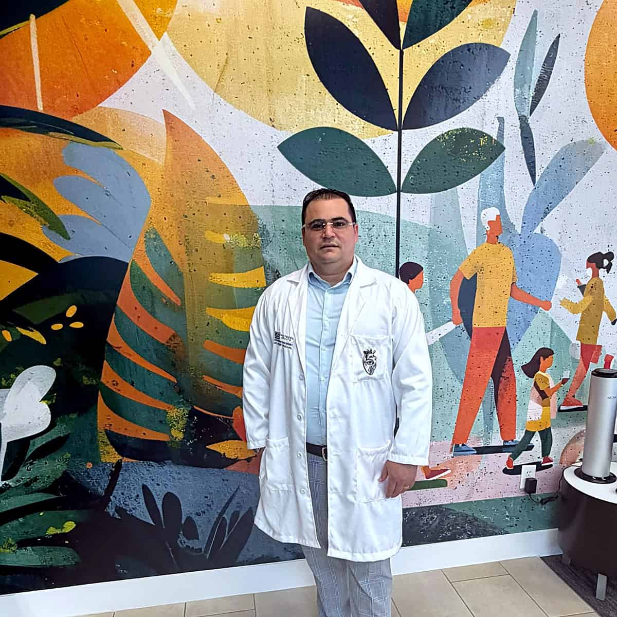 Dr. Hendry Pascual in front of the community wellness mural at PassQual Health